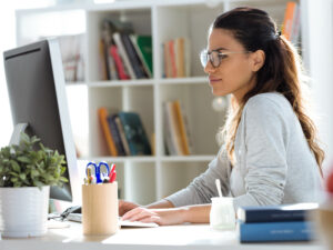 Woman sitting at desk looking at computer screen. | Tips For Applying For A Mortgage: Do’s And Don’ts